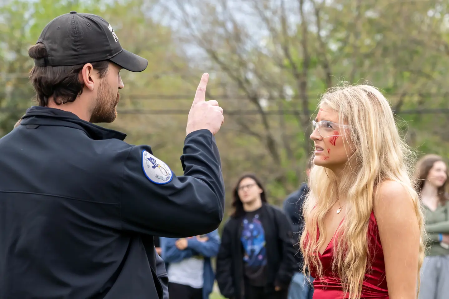 Police officer doing a field sobriety test on one of the participants in the mock crash in front of the group of students observing the mock crash.