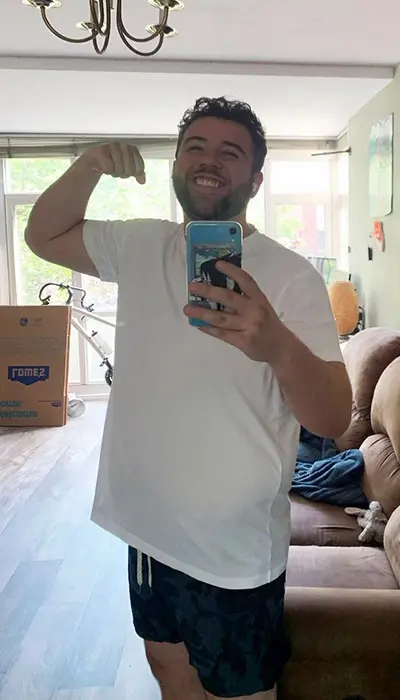 Julian O'Neil flexes his bicep while standing in his living room.