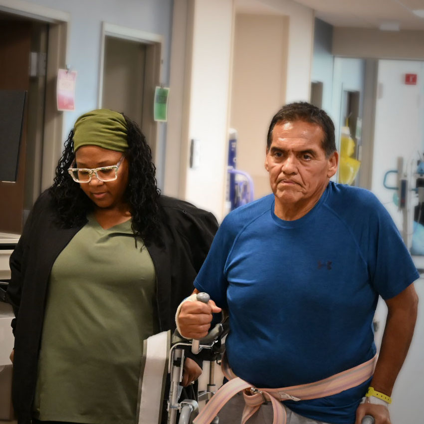 Physical therapist walking with a male physical therapy patient in Methodist Rehabilitation Hospital.
