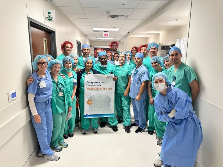 Dr. Saibal Kar and the cardiac care team pose with a poster of a medical device that treats atrial fibrillation.