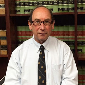 Mark Nathan smiles for the camera, while seated in front of shelves of law books.