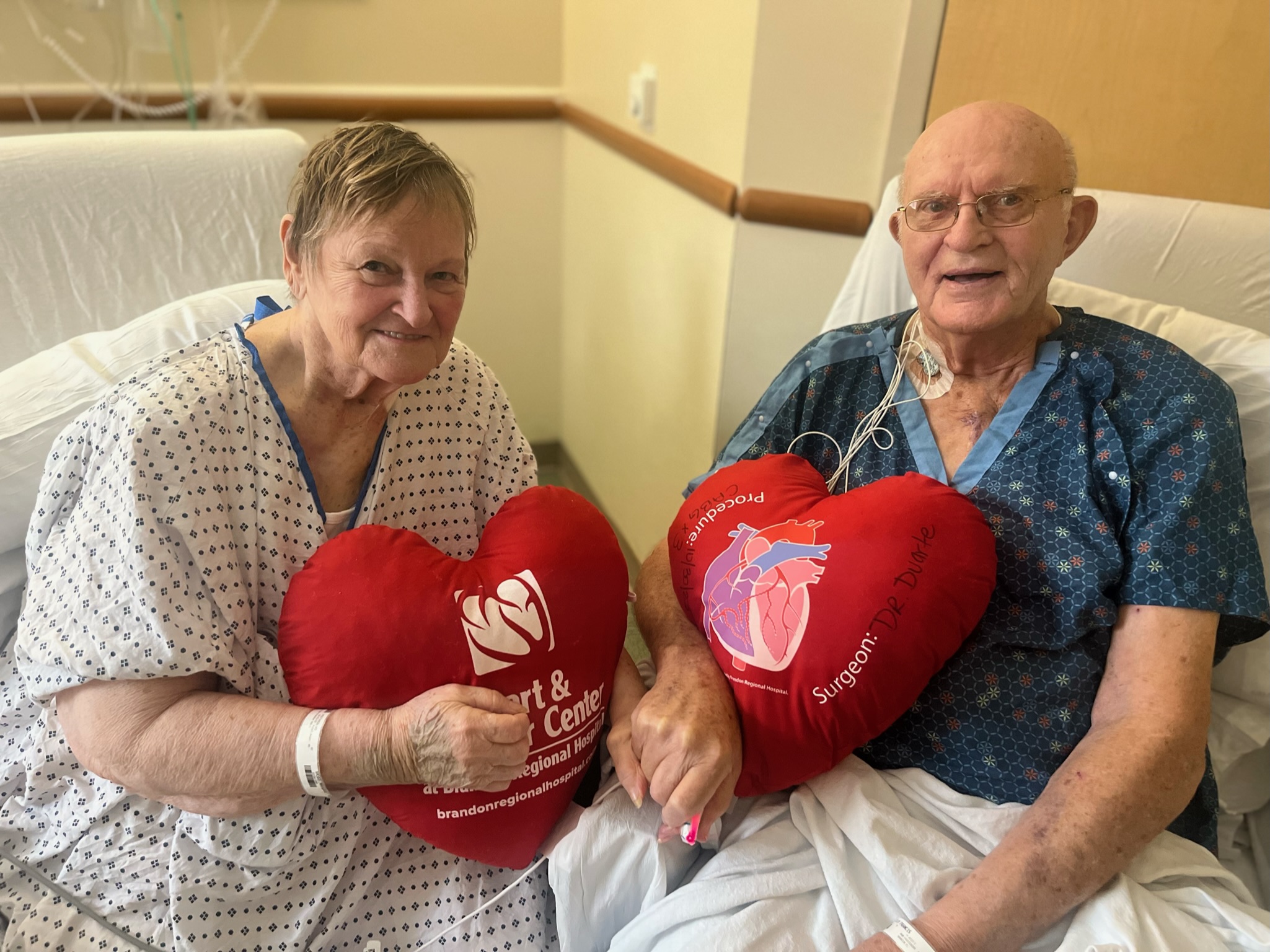 Phil and Margaret Vaske sitting next to each other with heart pillows