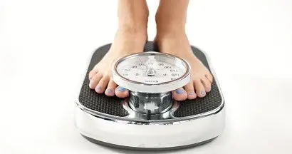 A person's feet with painted toenails standing on a scale.