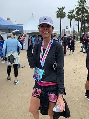 Andrea Doctor having a drink after a marathon run, with other participants behind her.