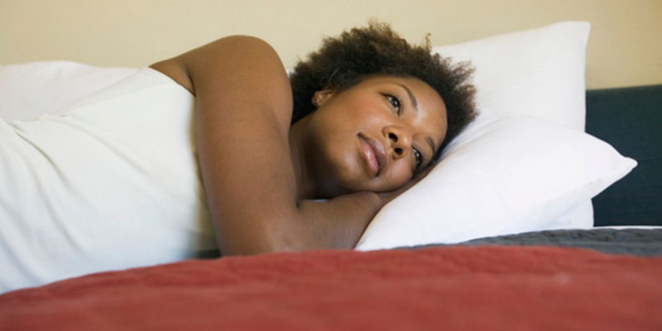 A woman lies in bed, looking tired after suffering from insomnia.