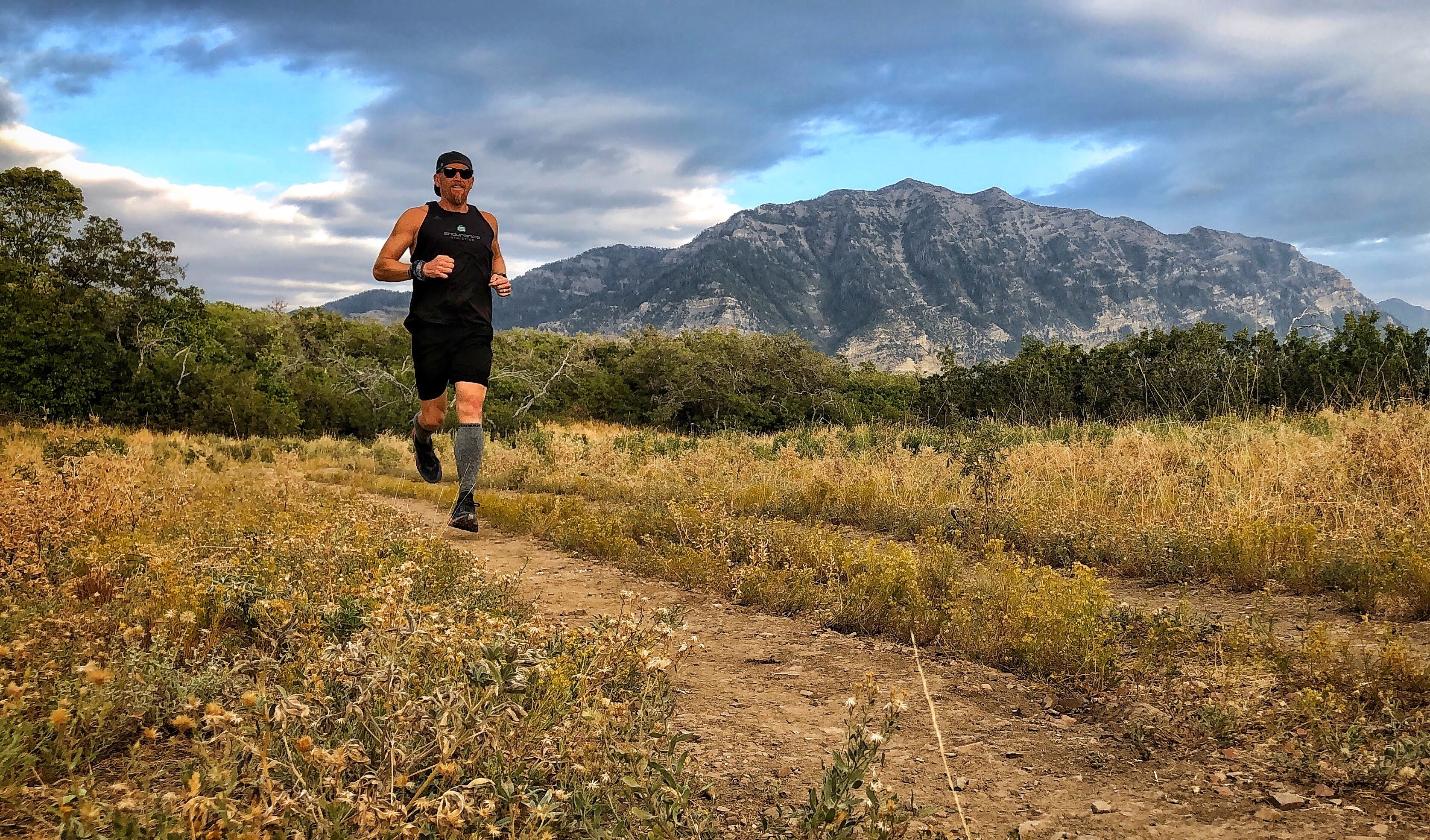 Aaron Jensen running on a path with a mountain behind him.