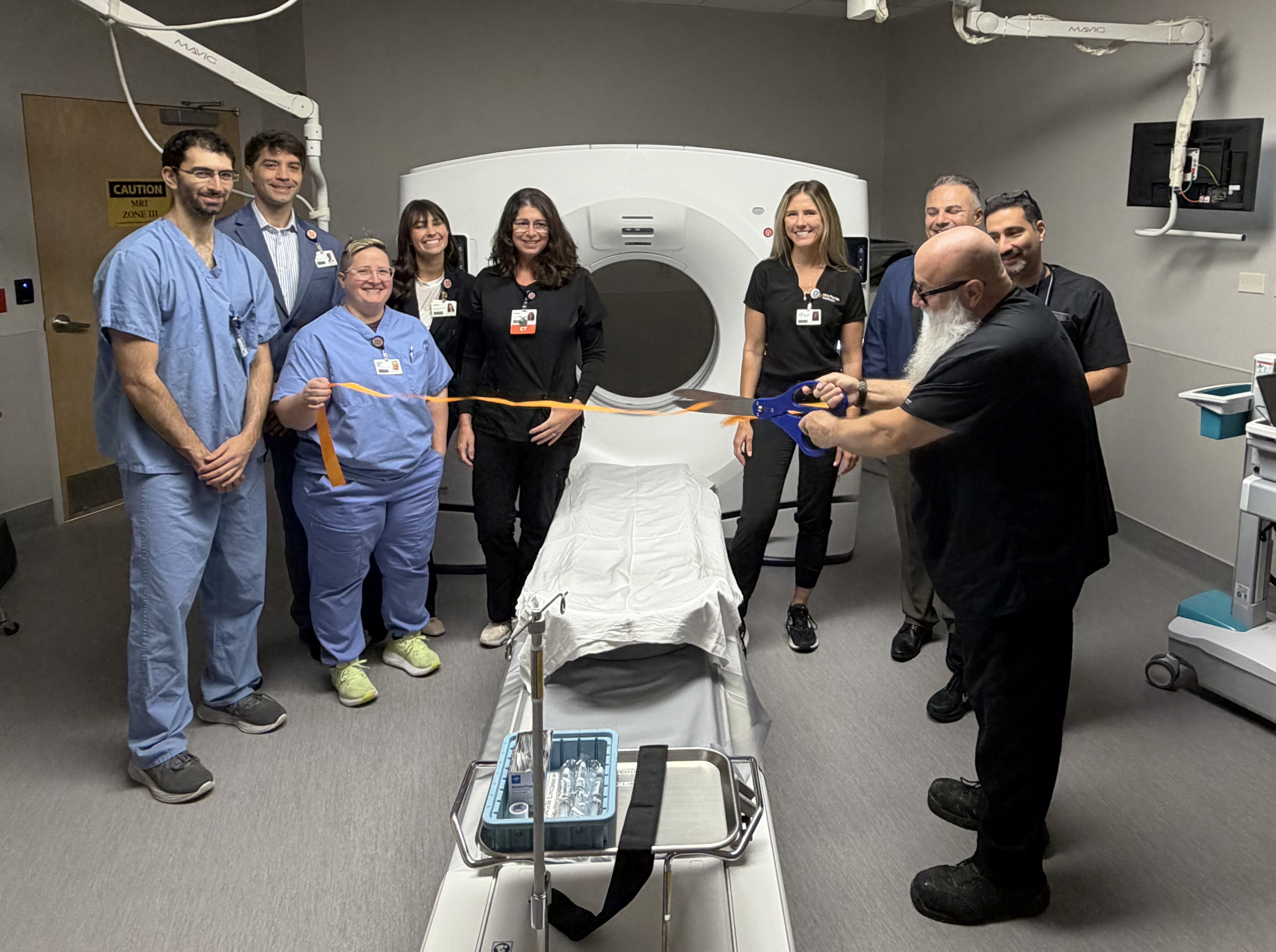 The radiology team stands next to the new CT Machine during a ribbon cutting