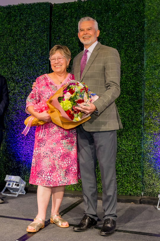 Betty Nuñez holds a bouquet of flowers while standing next to Greg Seiler, CEO of Methodist Hospital Metropolitan