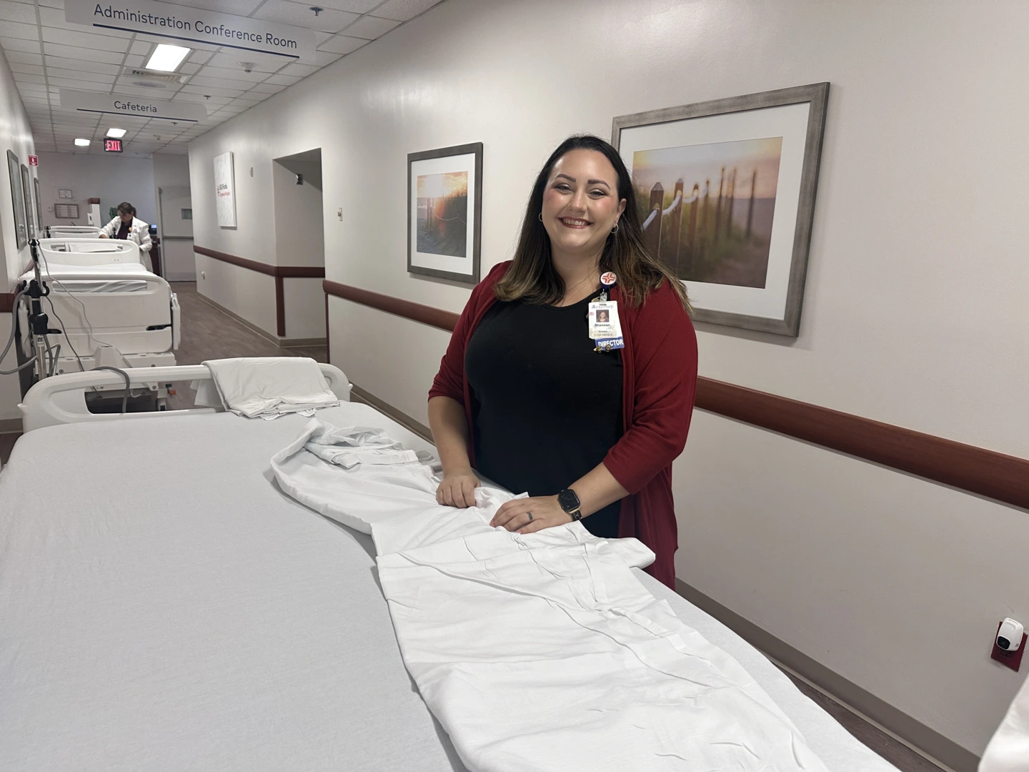 Clinical Informatics Director Shannon Driscoll stands with fresh linens next to a new patient bed.
