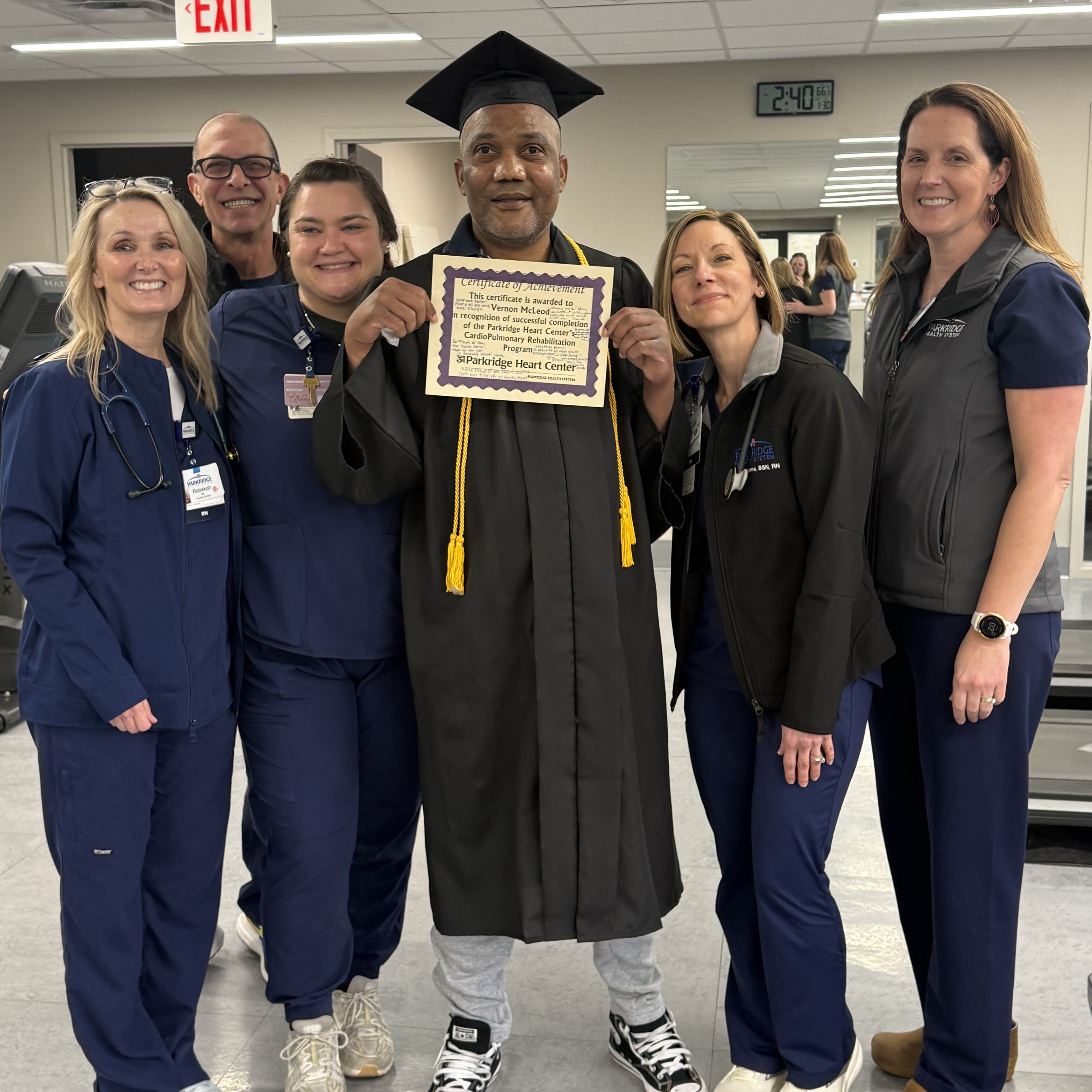 Healthcare staff and Vernon McLeod with a graduation cap and gown, holding a certificate inside Parkridge Medical Center.