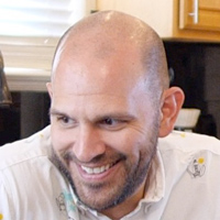 Zac Harris smiles while wearing a white button-up shirt.
