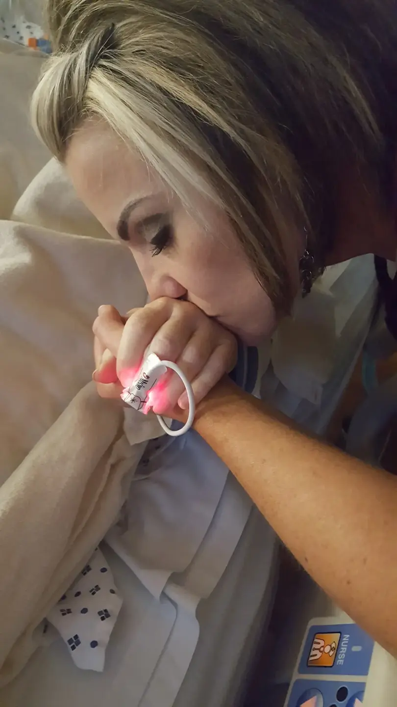 Gina Corry kissing her mothers hand in hospital.