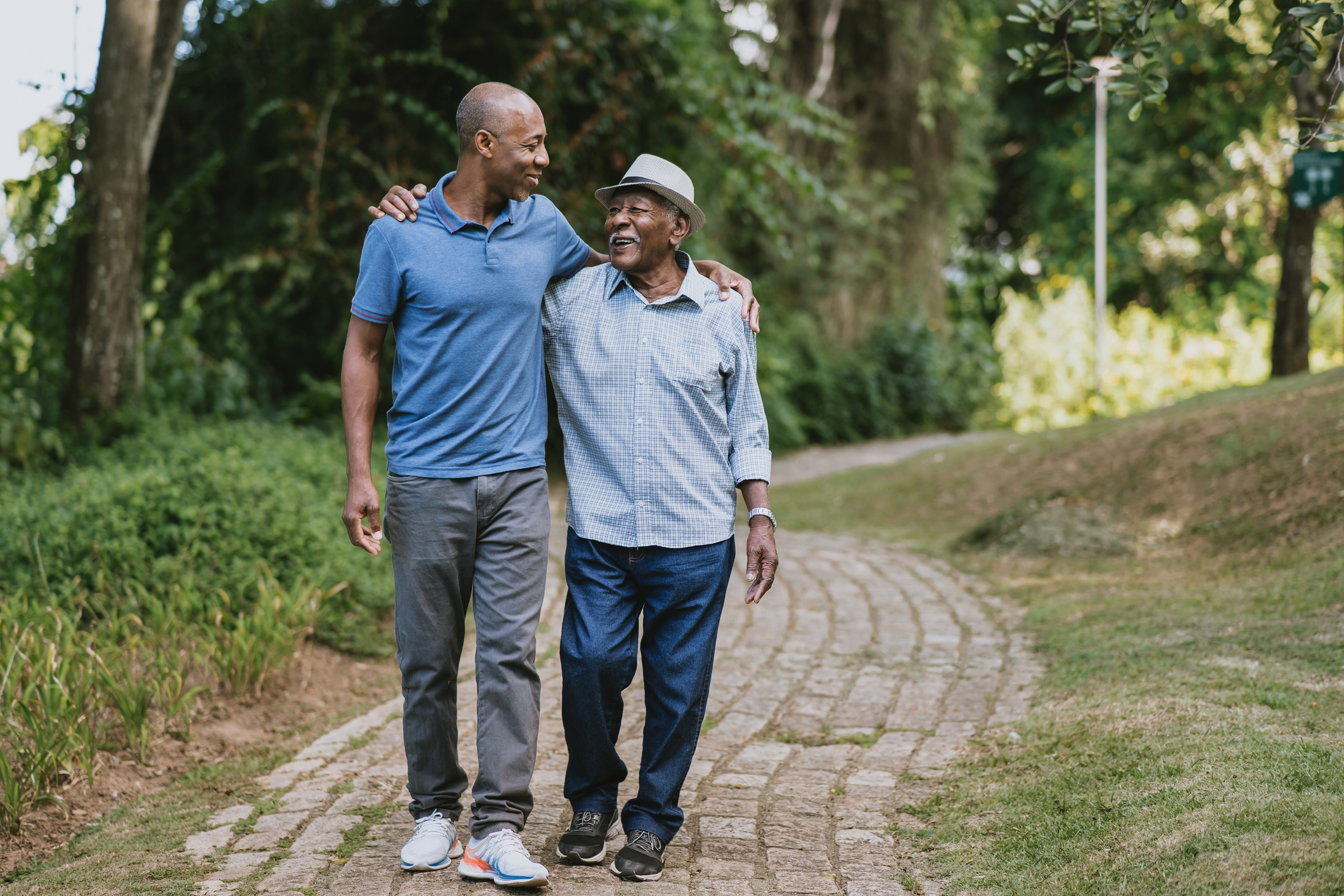 Elderly father and adult son walking in a park.