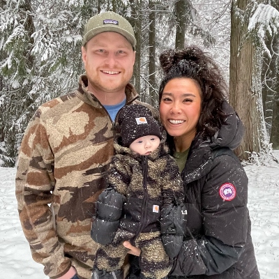 Dianne and her partner Bryce pose outdoors in the snow with baby Isaac.