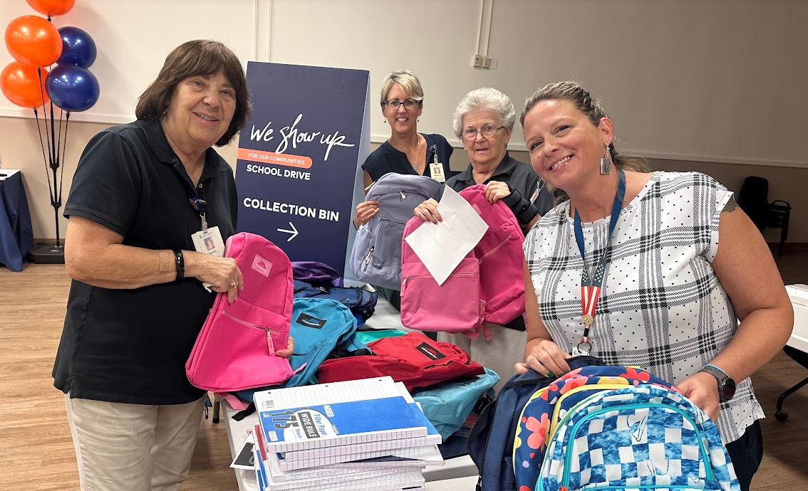 HCA Florida Englewood Colleagues and a volunteer pack colorful backpacks for students.