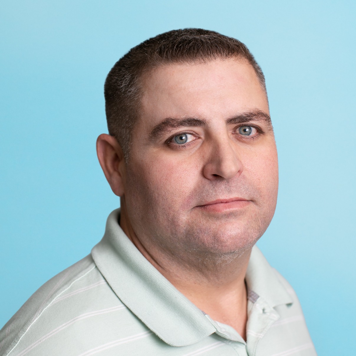 Daniel Owens smiles while wearing a green stripe golf shirt.