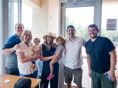 Karla O'Malley smile while standing with her family in a restaurant.