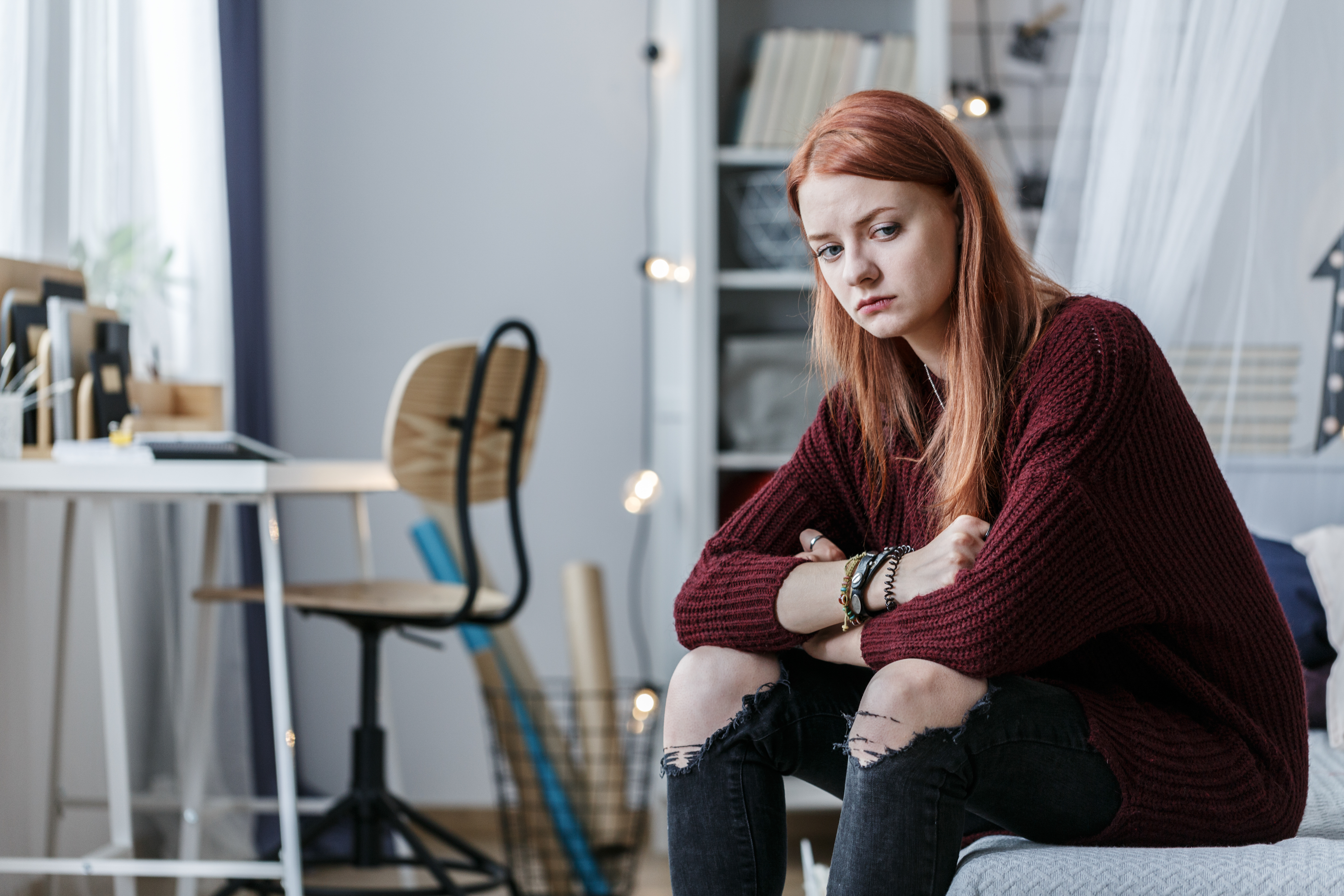 Sad young girl sitting on bed