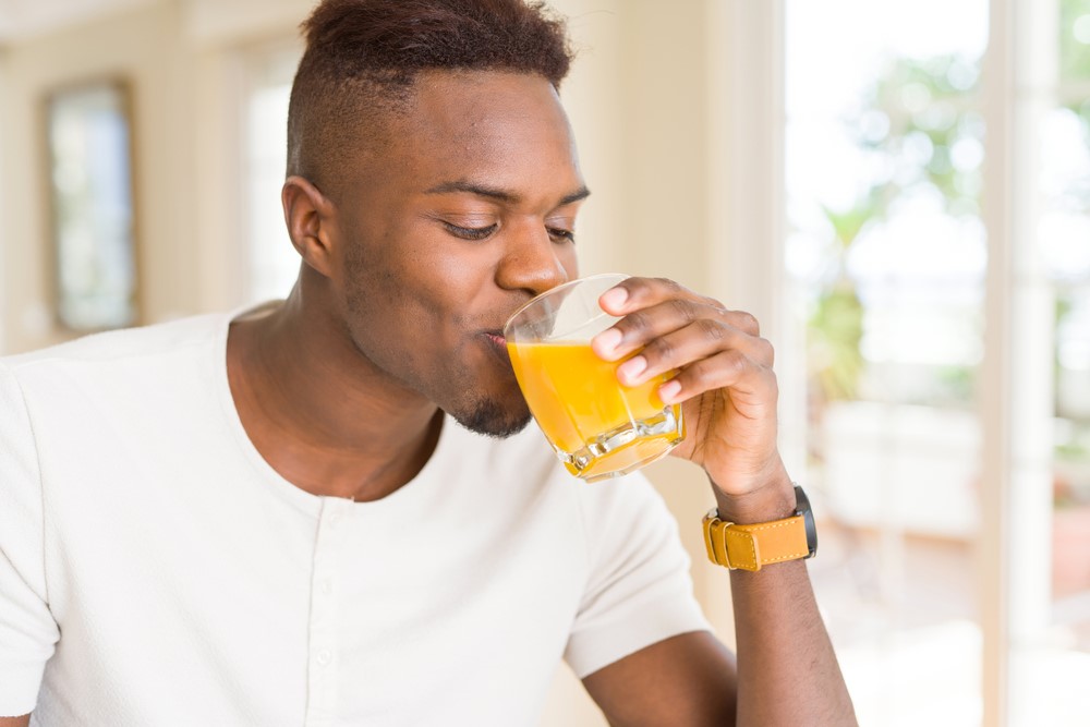 A man drinking a glass of orange juice.