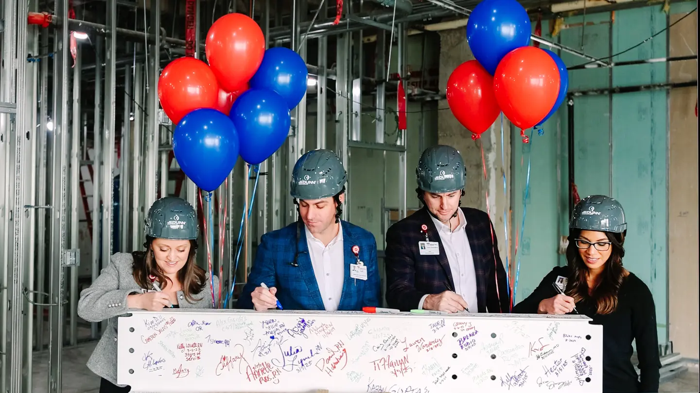 Team members signing the beam.