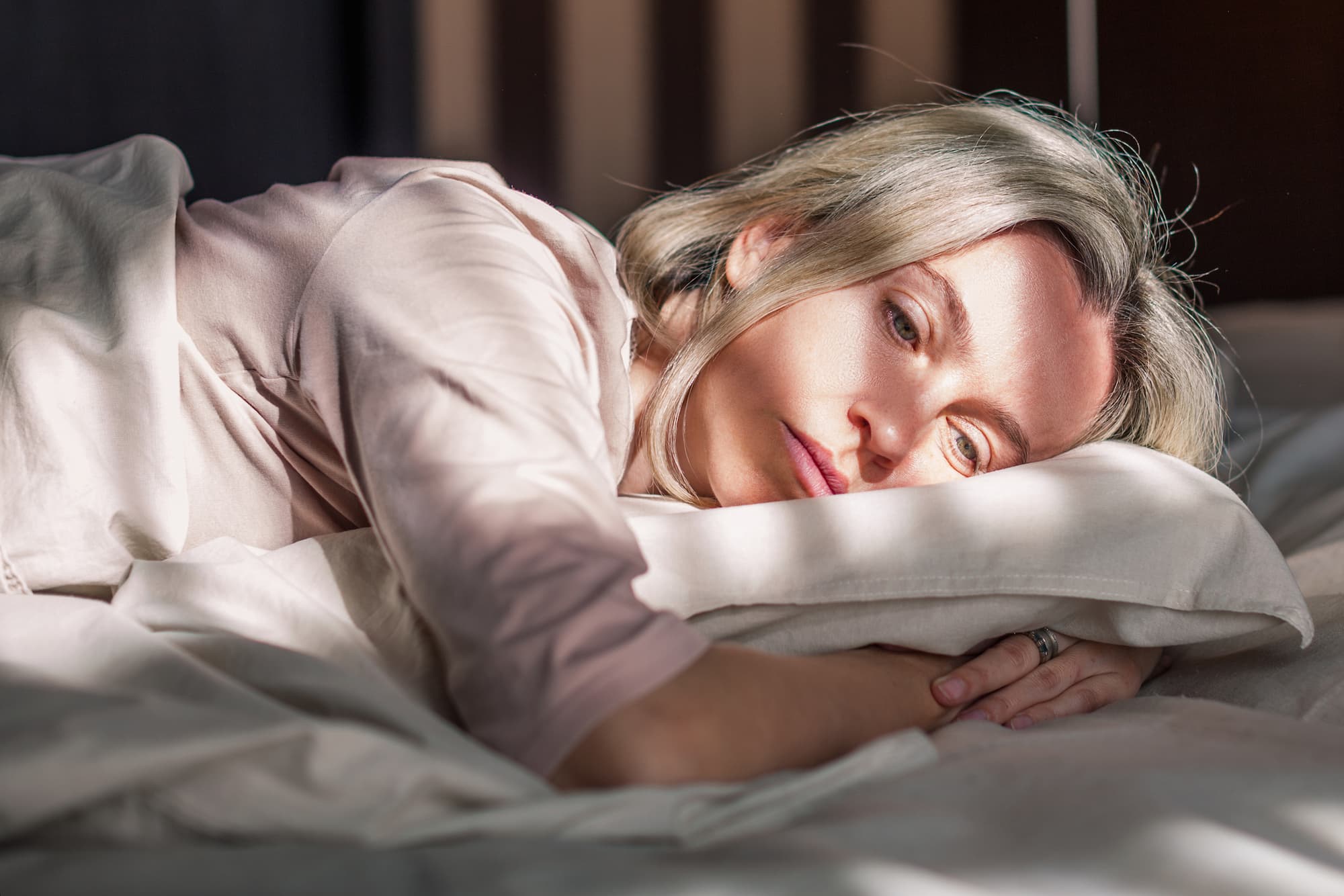 Stressed middle aged woman lying on bed at home and crying. 