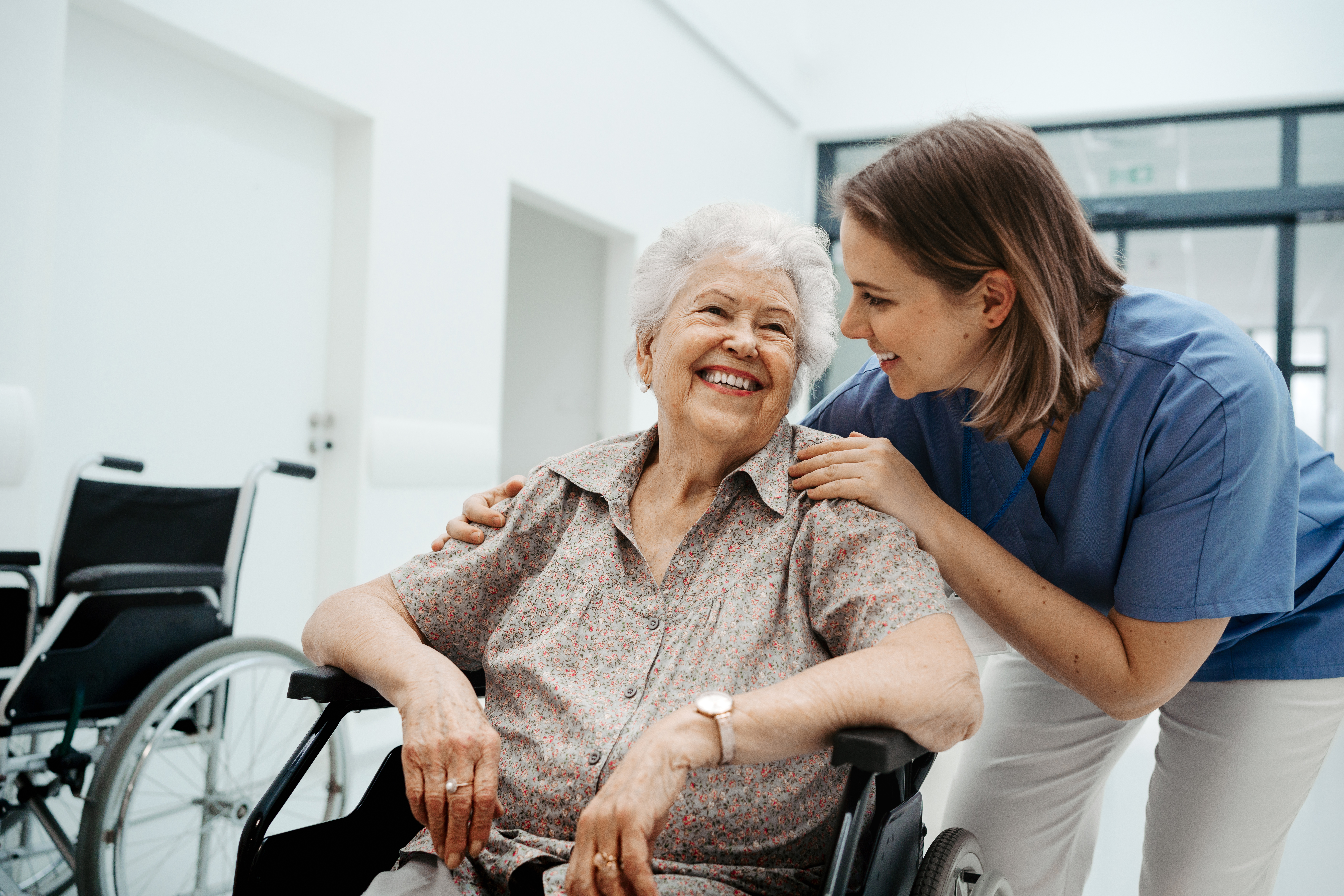 Nurse placing hands on elderly patient's shoulders.