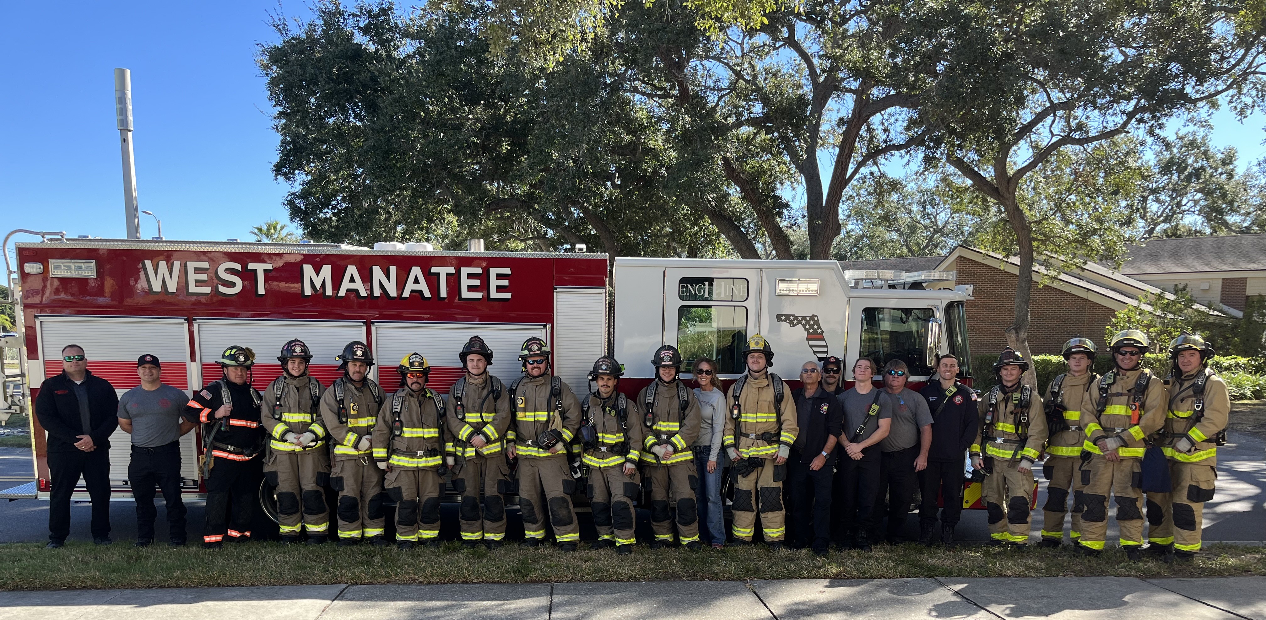 Blake hospital Surgeons, Trainers, Stuff and local Firefighters posing for a picture in front of a fire truck, that says "WEST MANATEE".