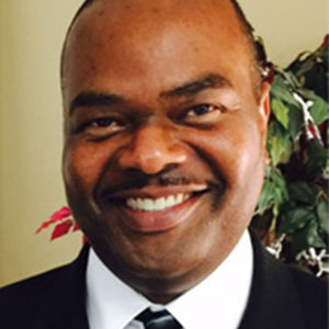 Bruce Dixon smiling and wearing a black suit.