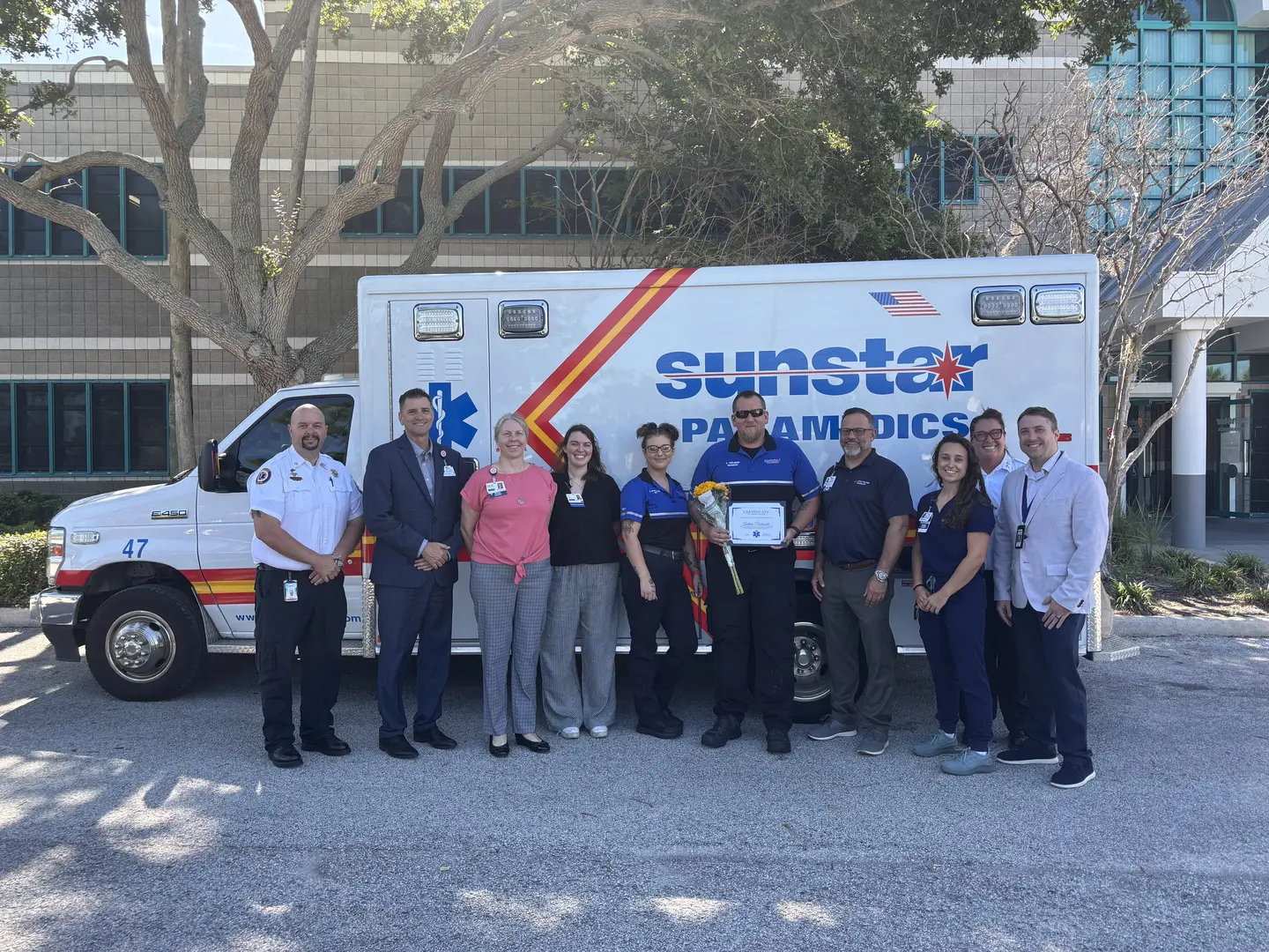 Paramedics standing in front of emergency vehicle with awards.