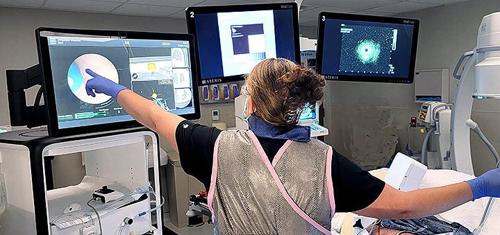 A nurse pointing at a screen while helping to conduct a robotic lung bronchoscopy.