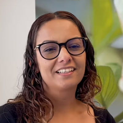 Janet Olivo smiles while wearing a black shirt and black-rimmed glasses.