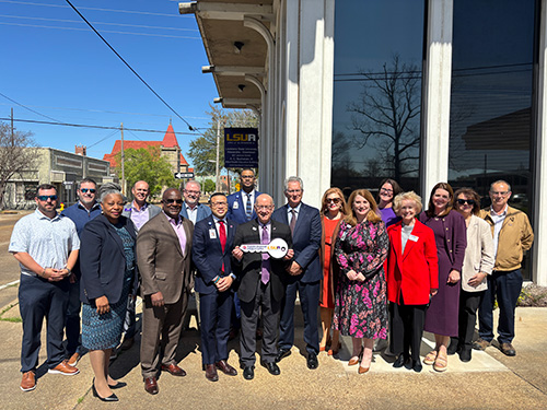Rapides Regional male and females executives and Lousiana State University officials gathered in large group outdoors.