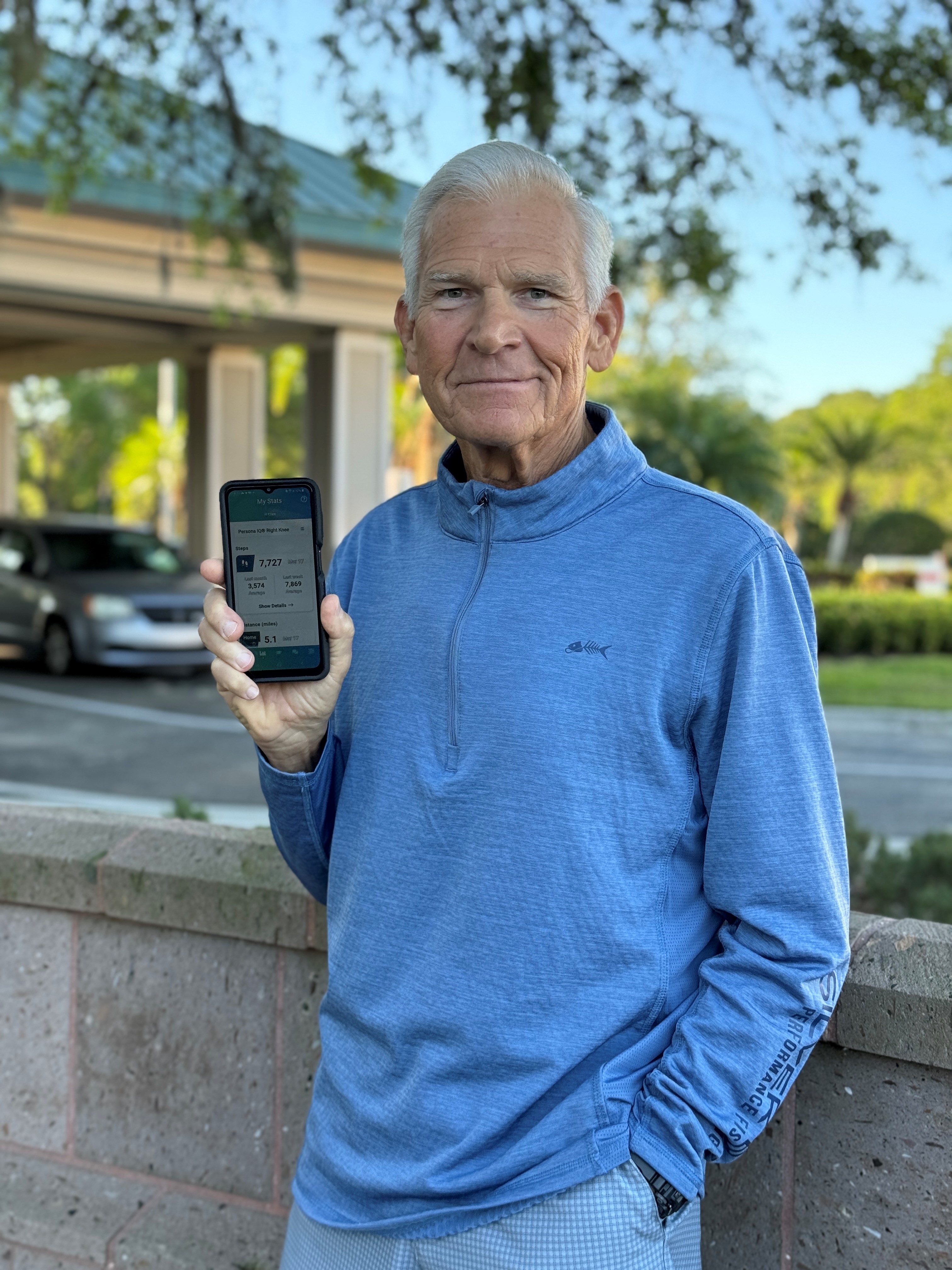 James Myers in blue shirt showing phone screen in hand