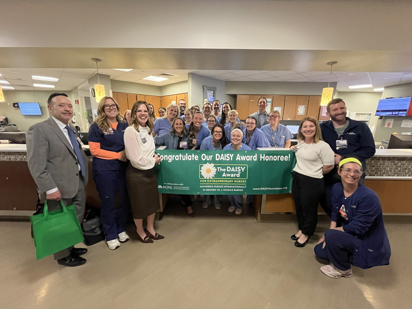 Ashlyn Holmes and coworkers pose with a banner of Daisy award winner.