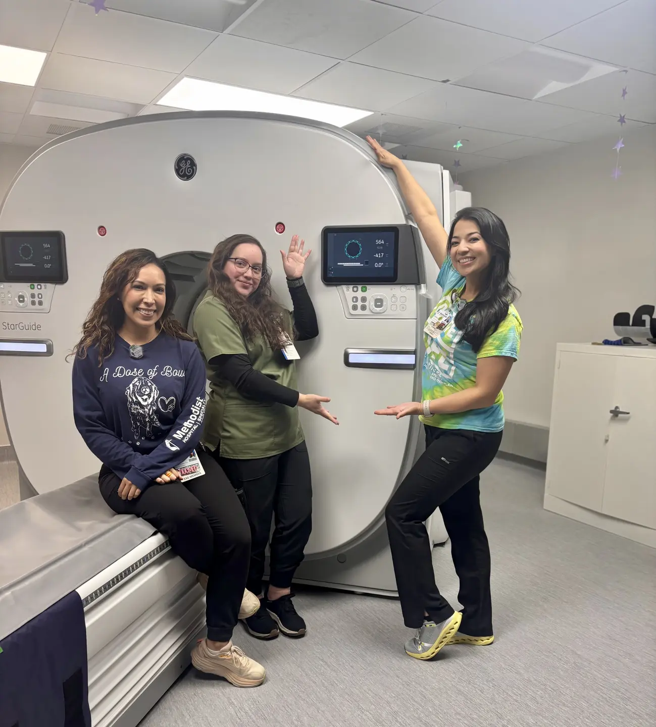 Three staff members pose with the new imaging machine.