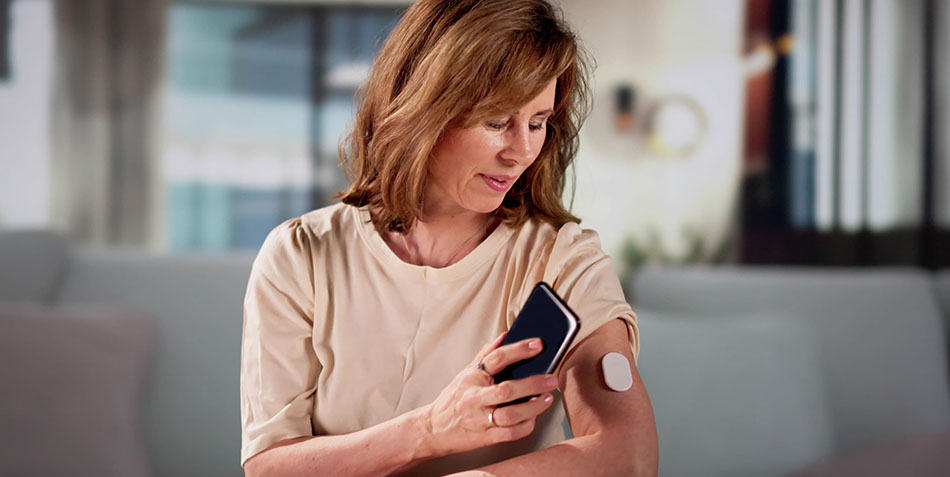 A female looking at a glucose device on her arm.