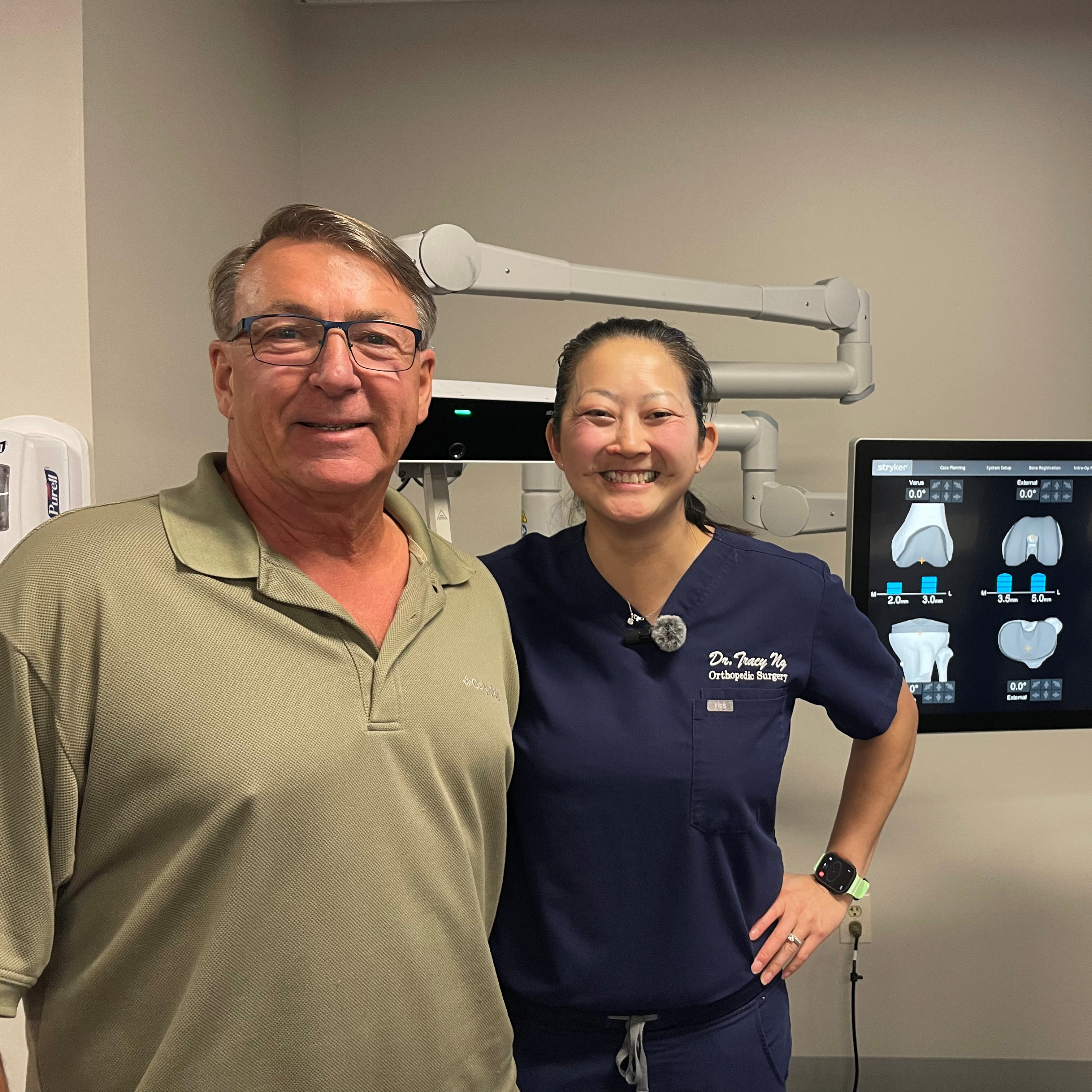 Patrick Decker and Dr. Ng stand smiling with robot behind them.
