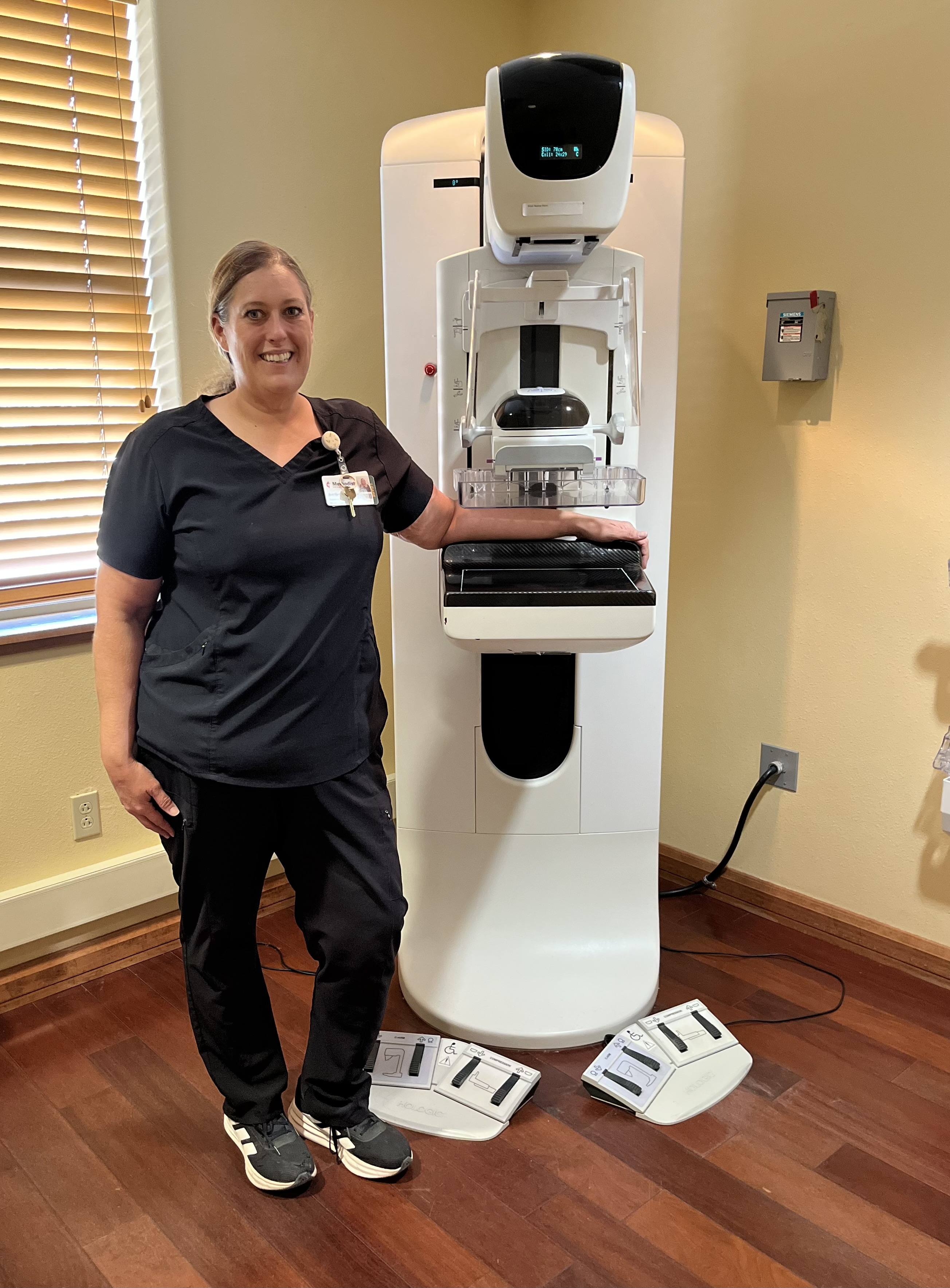 Staff member standing next to mammography machine.