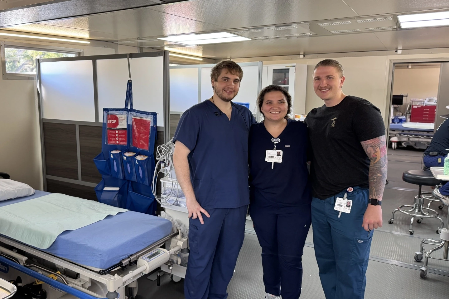 Three team members standing in the mobile ER unit ready to serve the community.