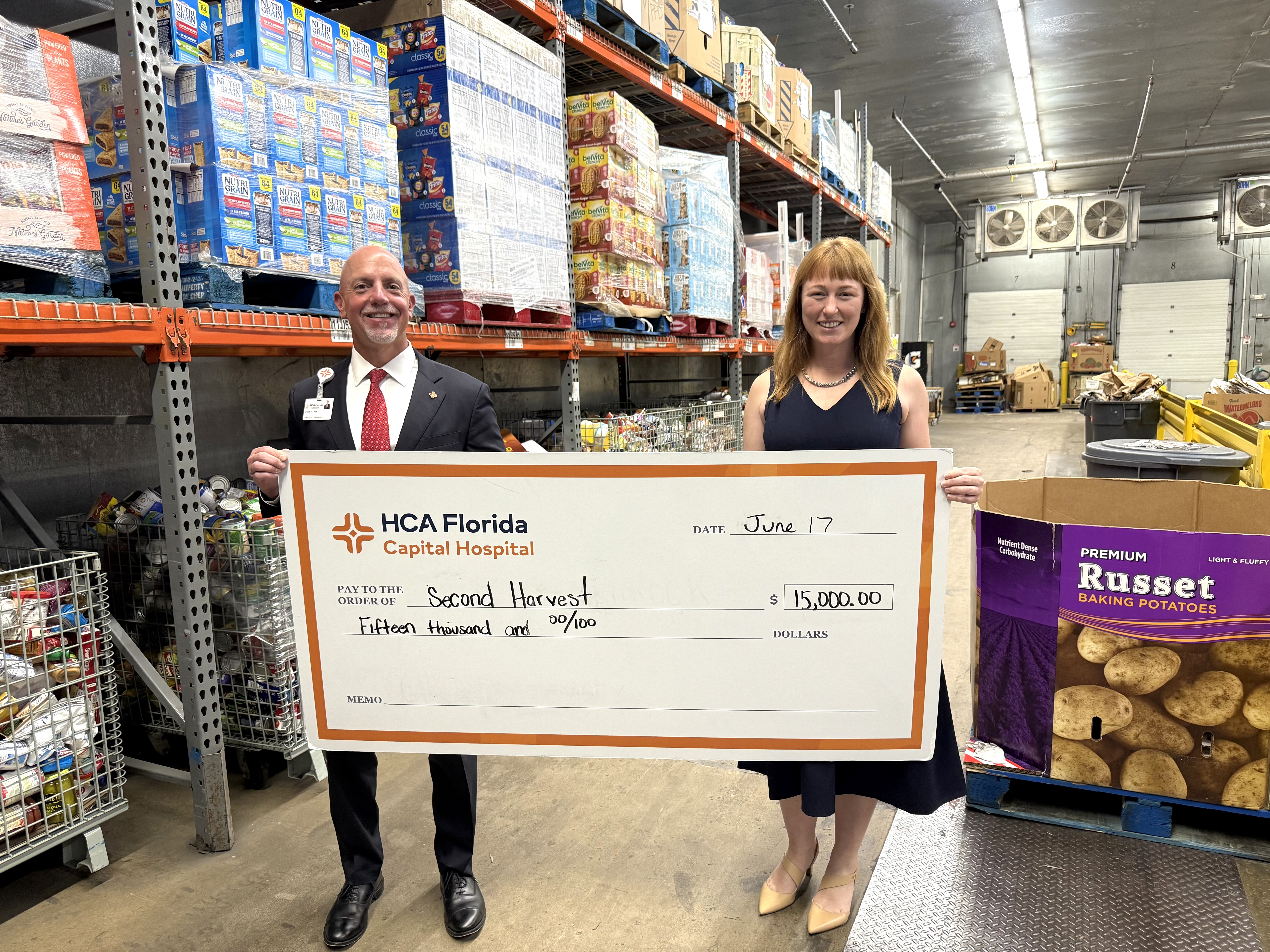 HCA representatives stand with large donation check in big box store.