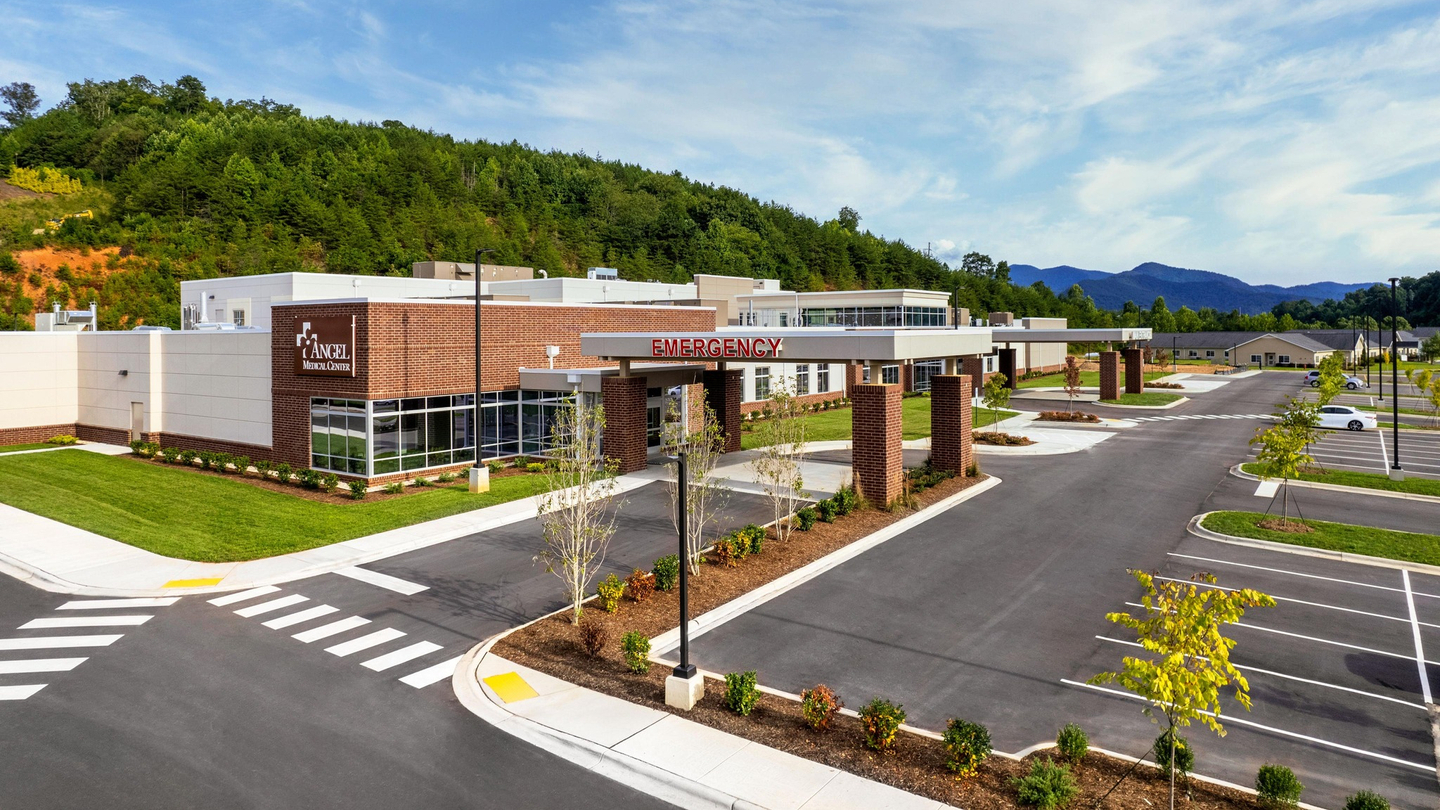 Exterior of Angel Medical Center, looking at the emergency room entrance and the main entrance in the background, with a parking lot in front of the building.