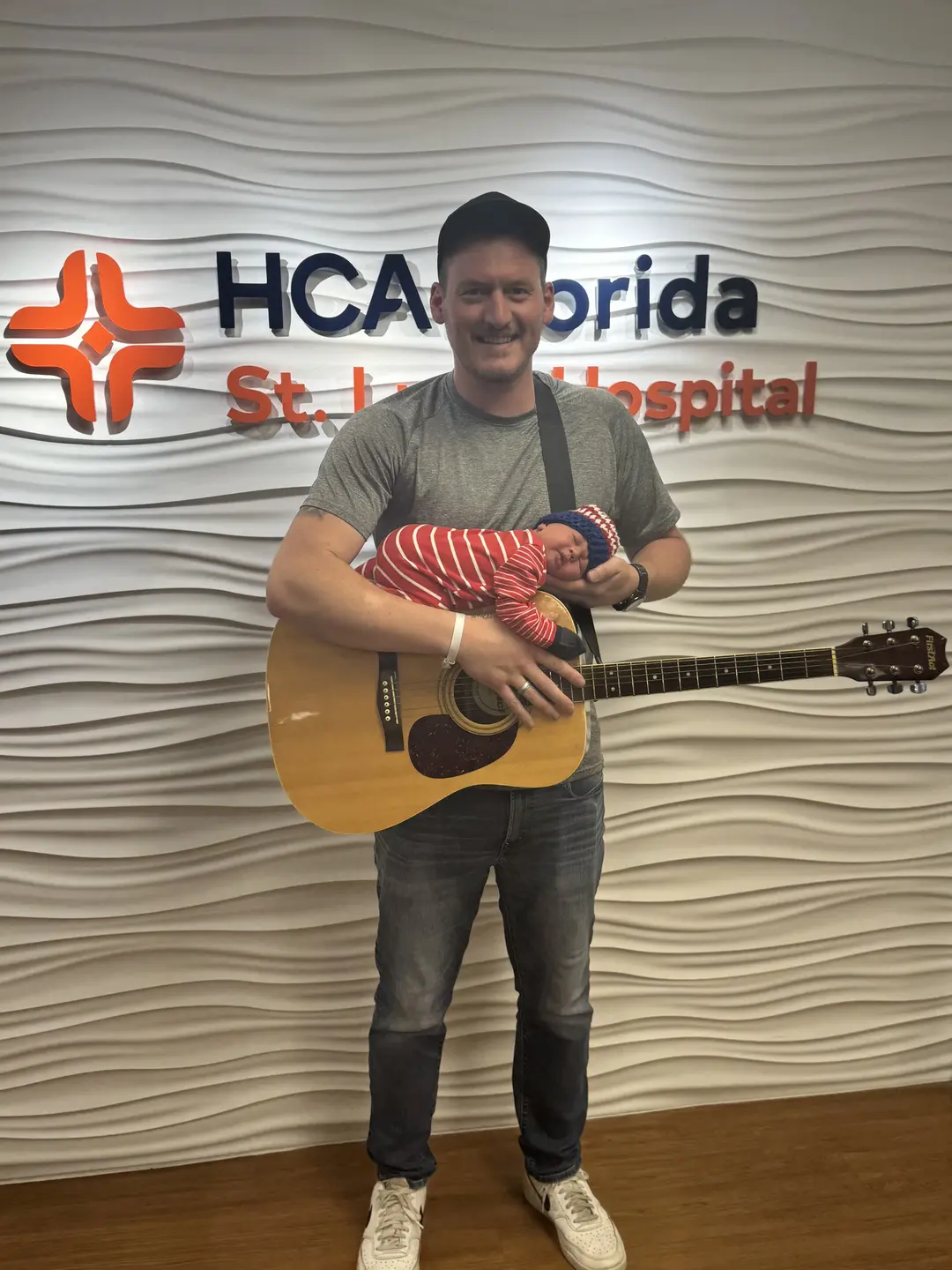 Colton and his newborn son posing with a guitar.