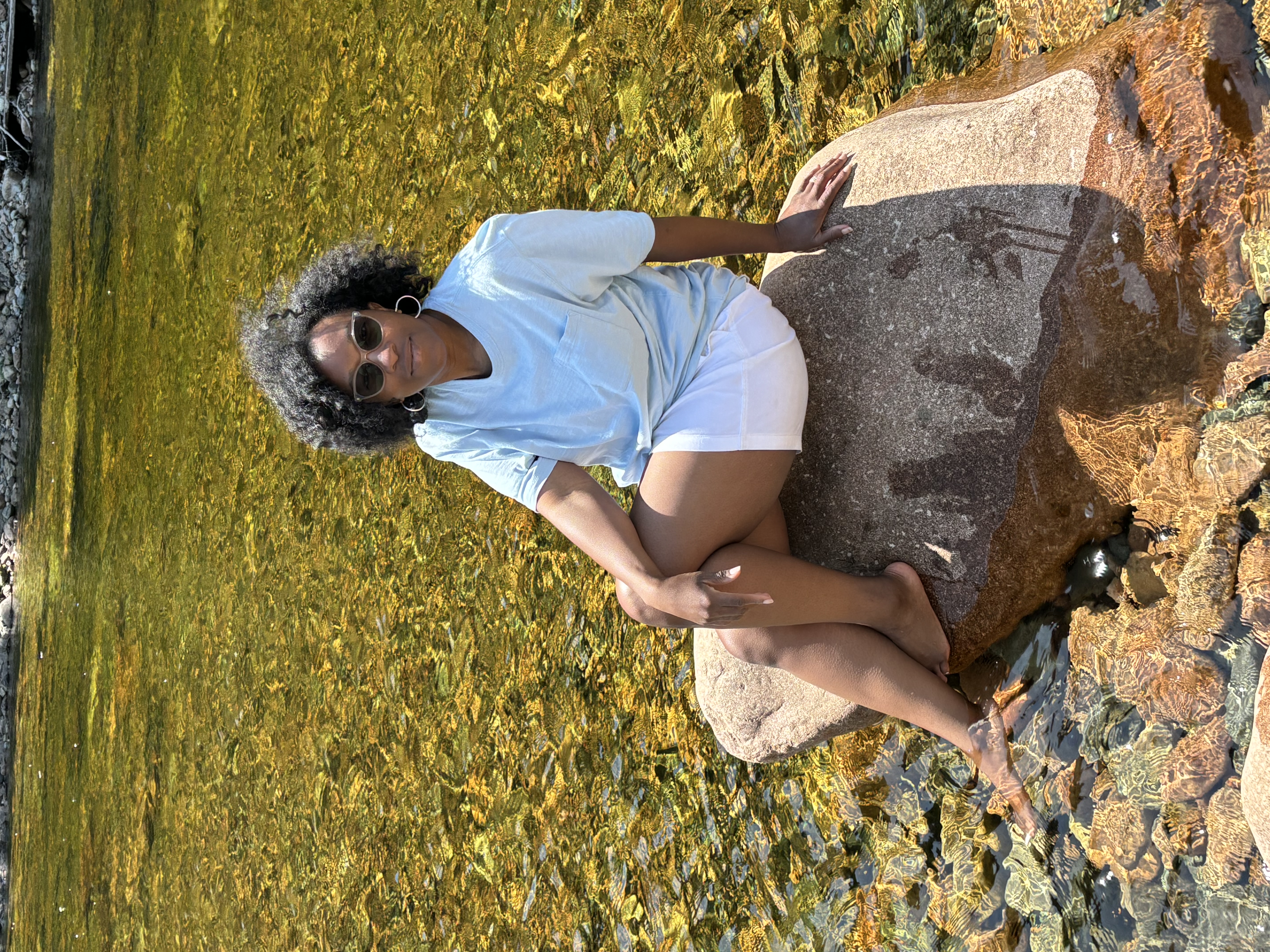 Dr. Jennifer Harned Adams sitting on a rock at a pond.