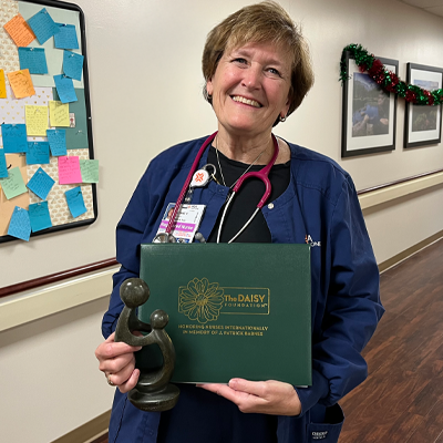 Lyne Picket smiling and holding her Daisy Award.