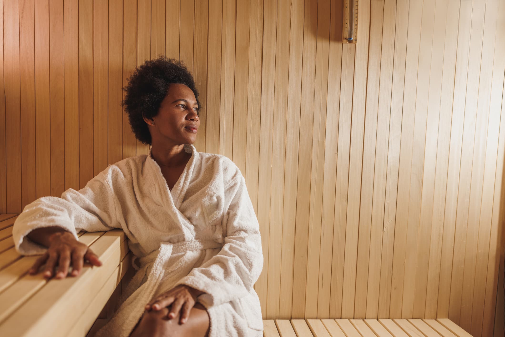 Woman wearing a terrycloth robe and relaxing in a sauna.