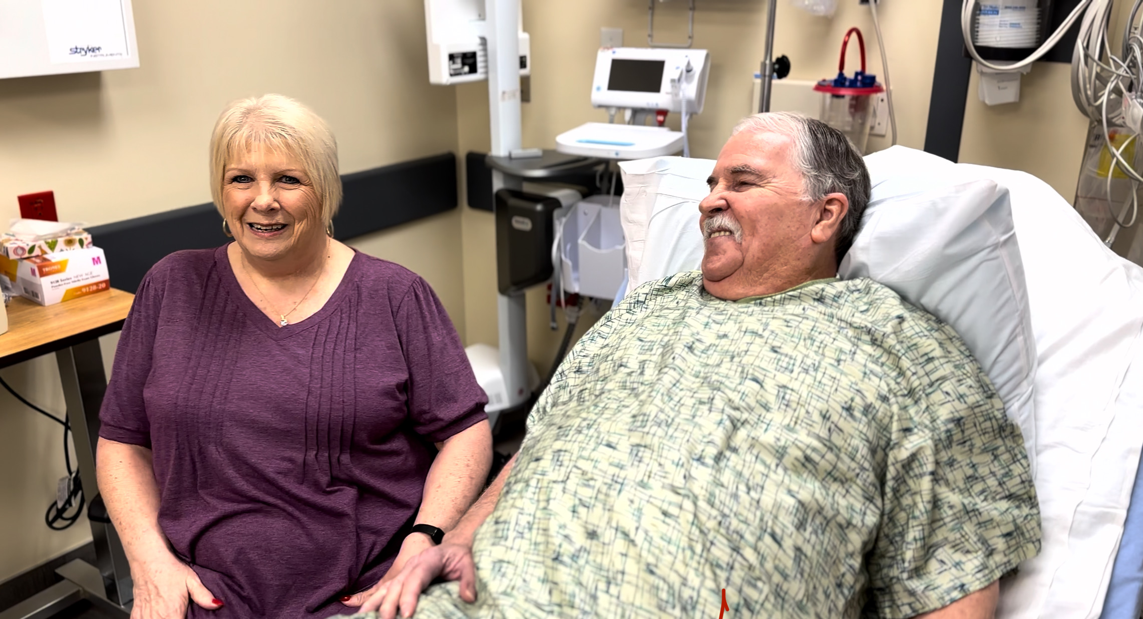 Peggy sitting next to David in the hospital.