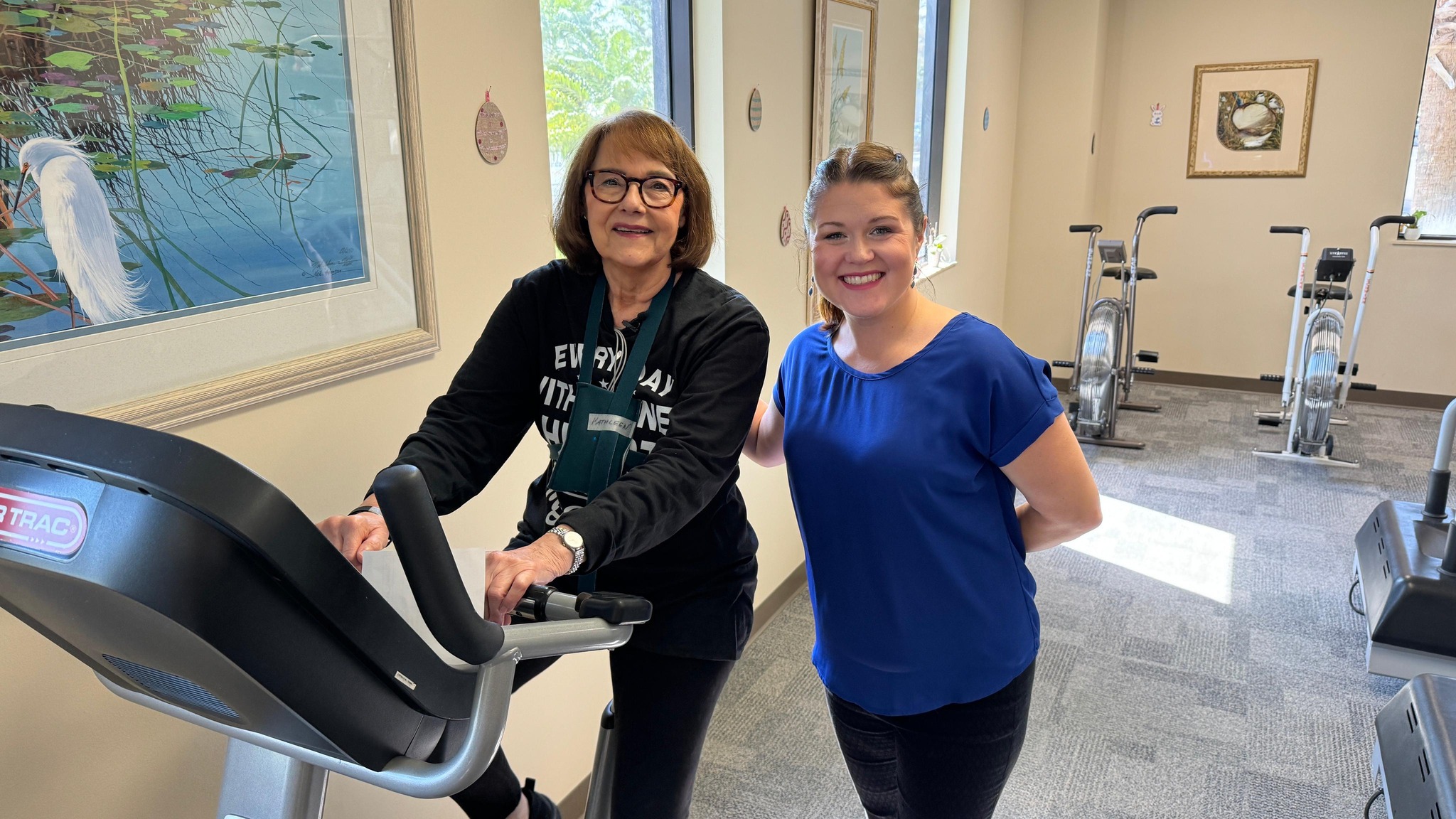 Woman sitting on bike with another woman standing next to her.