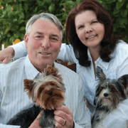 Geoffrey and his wife pose for a picture with their two small dogs.