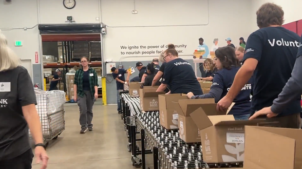 A group of HCA HealthONE employees volunteering at a table of cardboard boxes at the Food Bank of the Rockies