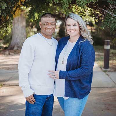 Jessie Gutierrez and his wife Megan pose together outside, smiling.